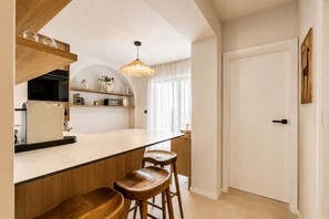 Eine moderne Küche mit Barbereich, Holzstühlen und einer hängenden Leuchte.