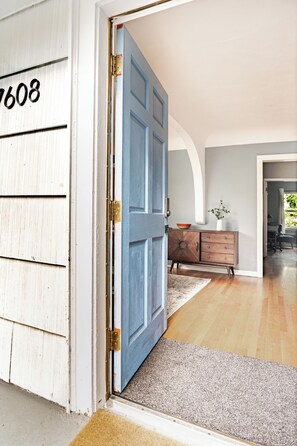 Um quarto com porta de madeira, cômoda e tapete.
