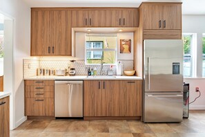 Una cocina moderna con armarios de madera, un refrigerador de acero inoxidable y un lavavajillas.