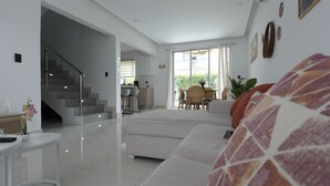 Ein modernes Wohnzimmer mit einer Couch, einem Essbereich und einer Treppe, die zu einer oberen Etage führt.