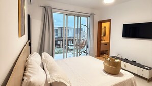Ein Schlafzimmer mit Bett, Deckenventilator, Fernseher und Blick ins Freie.