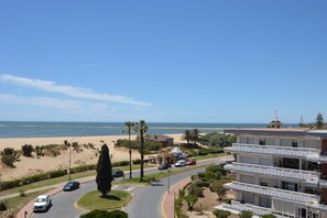 A coastal road with a beach view, a roundabout, and a multi-story building with balconies. - Alcaudón 86 - Two Bedroom Apartment, Sleeps 4 (Punta del moral)