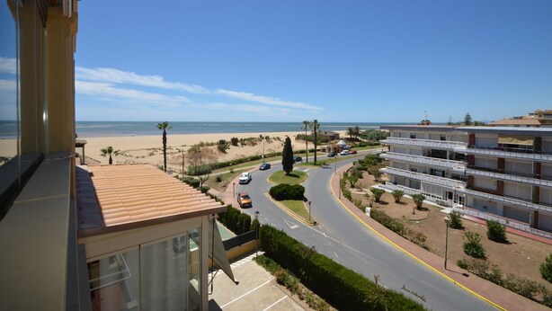 A coastal residential area with a road leading to a beach, surrounded by multi-story buildings with balconies. - Alcaudón 86 - Two Bedroom Apartment, Sleeps 4 (Punta del moral)
