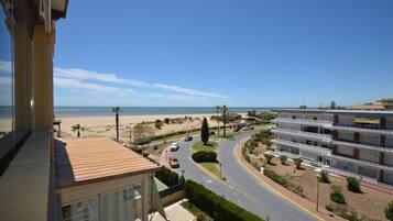 Uma área residencial costeira com uma estrada que leva a uma praia, cercada por edifícios altos com varandas.