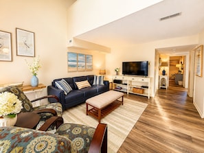 A living room with a sofa, coffee table, TV, and artwork on the wall.