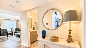 A hotel room with a wooden floor, a sitting area with chairs, a vanity with a mirror, a lamp, and a vase. - Upscale Rehoboth Retreat Minutes from Beach & Boardwalk (Rehoboth Beach)