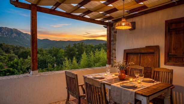Une table à manger dressée pour deux personnes, avec vue sur les montagnes et les arbres.