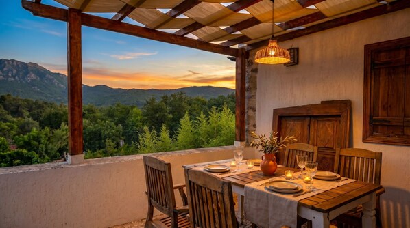 A dining table set for two with a view of mountains and trees.