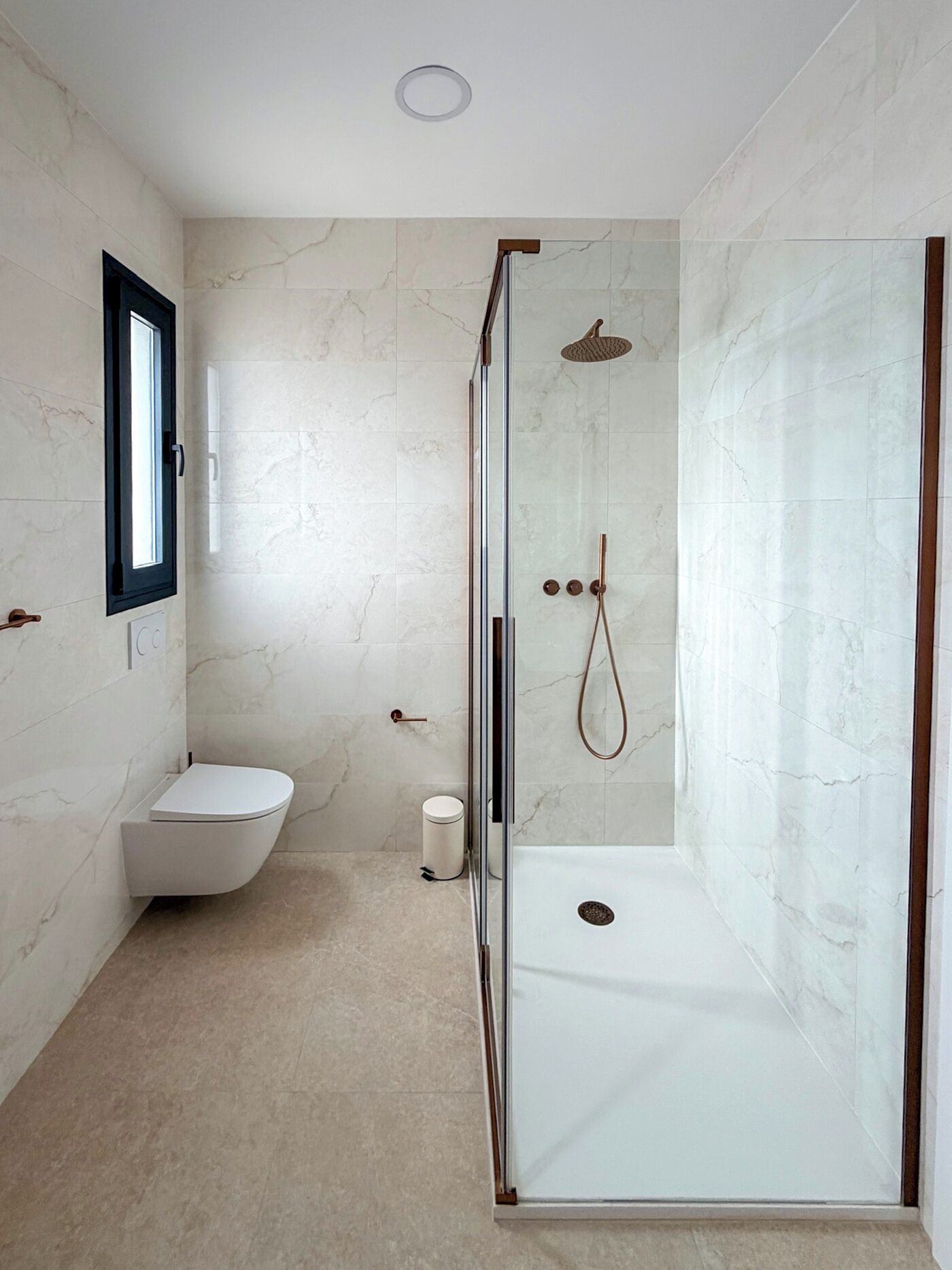 A bathroom with a glass-enclosed shower, a toilet, and a sink.