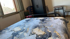 Ein Schlafzimmer mit einem Bett, einem Kleiderschrank, einem Sessel und einem kleinen Tisch.