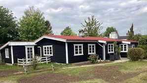 A two-story black building with a red roof, white trim, and multiple windows. - 6 Person Holiday Home in Vaeggerlose (Vaeggerlose)