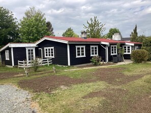 A two-story black building with a red roof, white trim, and multiple windows. - 6 Person Holiday Home in Vaeggerlose (Vaeggerlose)