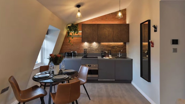 Eine moderne Küche mit Essbereich, ausgestattet mit einem Backofen, einer Spüle und einem Esstisch mit Stühlen.