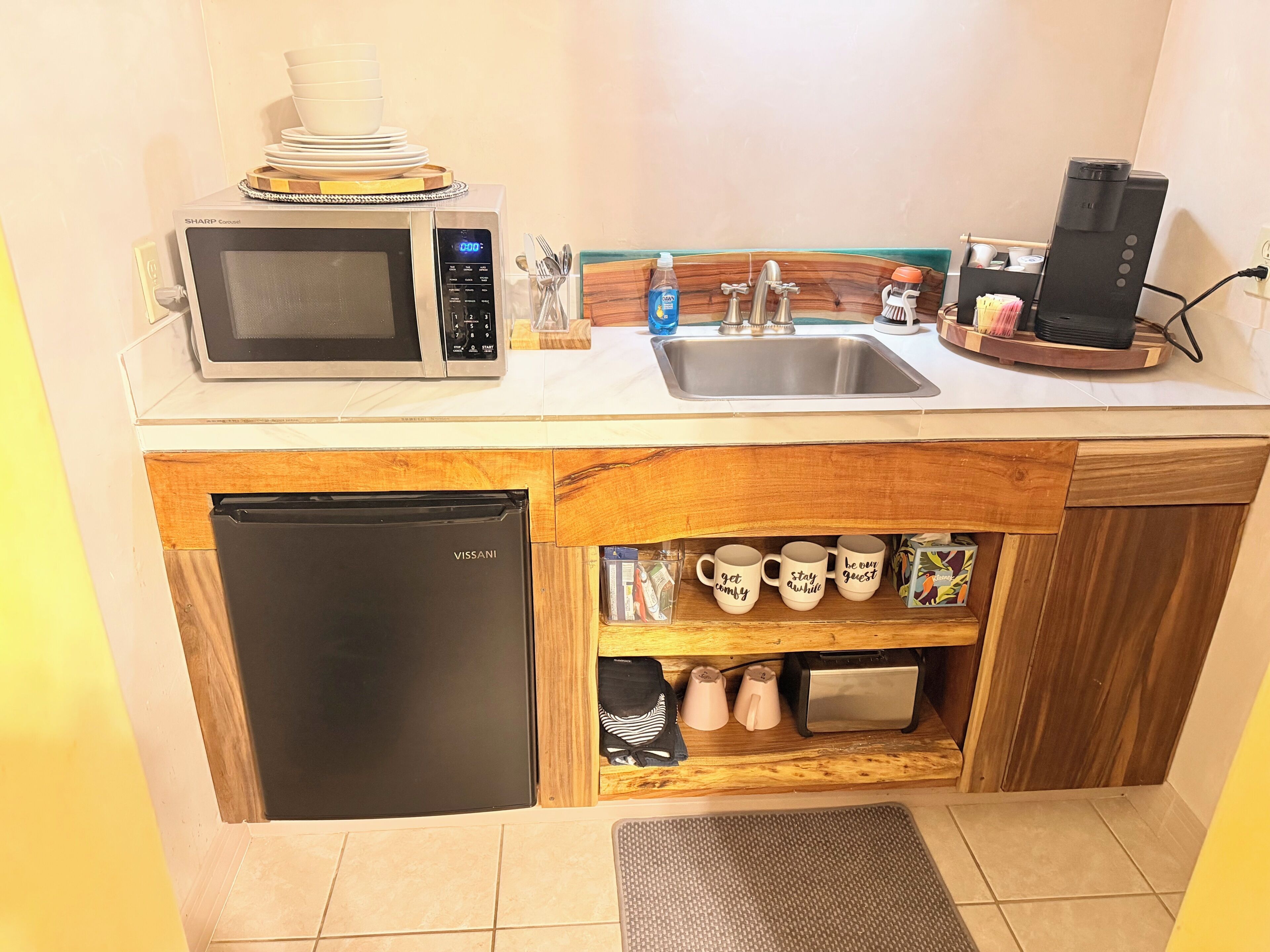 Cocina compacta con microondas, fregadero, cafetera y refrigerador.