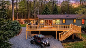 Una cabaña con terraza, un vehículo y un letrero que indica Trailhead Grill.