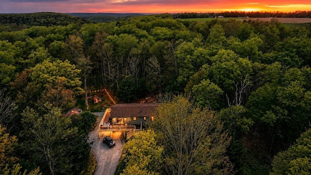 Una casa rodeada de un bosque frondoso con una vista despejada del atardecer.