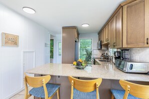 A kitchen with a central island, wooden cabinets, and a microwave.