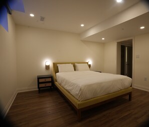 Ein Schlafzimmer mit einem hölzernen Bett, Nachttischen und einer Tür.