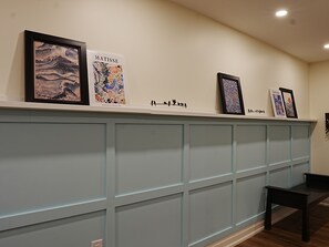 Eine Wand mit gerahmten Kunstwerken, einer Bank und blauen Wandverkleidungen.