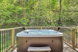 Ein Whirlpool auf einer Holzterrasse mit Blick auf einen Wald.