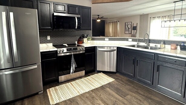 Una cocina moderna con un refrigerador de acero inoxidable, microondas, horno y lavavajillas.