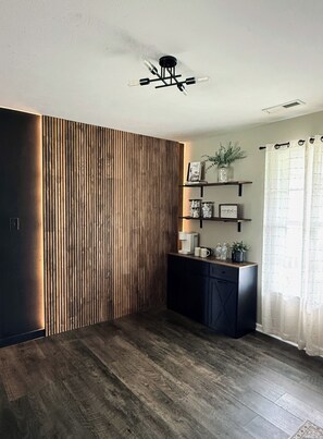 Quarto com parede de ripas de madeira, um armário preto com prateleiras e um ventilador de teto.