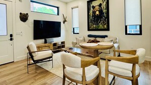 A modern living room with a flat-screen TV, wooden furniture, a ceiling fan, and a bear painting.