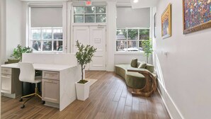 A modern interior with a desk, seating area, and large windows. - Lux  Funk Suite W/2  Luxury Baths (New Orleans)