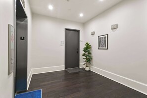 A hallway with a dark wooden floor, a door labeled '3A', a potted plant, and a framed picture on the wall. - Lux  Funk Suite W/2  Luxury Baths (Top Floor) (New Orleans)