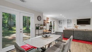 Una sala de estar moderna con comedor, un sofá, un televisor y vistas al exterior.
