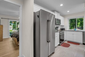 A modern kitchen with white cabinets, stainless steel appliances, and a view of greenery outside. - Renovated Pet-friendly 3br 2.5ba Fenced House in Charming Mauldin and EV Charger (Mauldin)