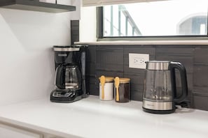 Eine Küchenarbeitsplatte mit einer Kaffeemaschine, einer Glas-Kanne und zwei Gläsern mit Holzböden.