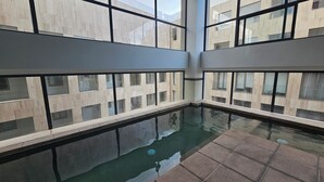 A modern indoor pool with clear glass walls, reflecting the building's architecture.