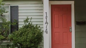 A house with a red door, a number '1174' on the wall, and a porch with a doormat. - Work Trip & Family Friendly - 3BR House in Historic Sayles. Long Term Stays (Abilene)