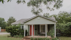 A single-story house with a front porch, a red door, and a small patio area. - Work Trip & Family Friendly - 3BR House in Historic Sayles. Long Term Stays (Abilene)