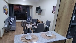 A modern living room with a sofa, dining table, chairs, and a TV mounted on the wall. - The yako and whiteman department (Lima)