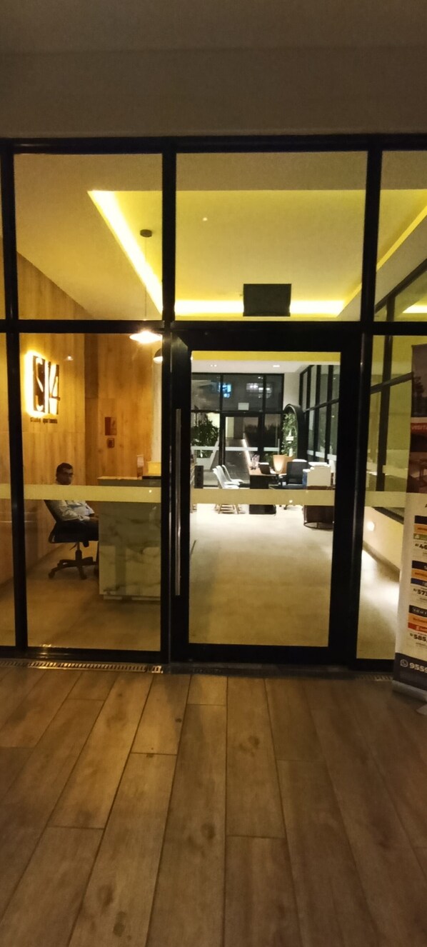 Un espacio de oficina con un mostrador de recepción, una silla y un escritorio con una computadora.