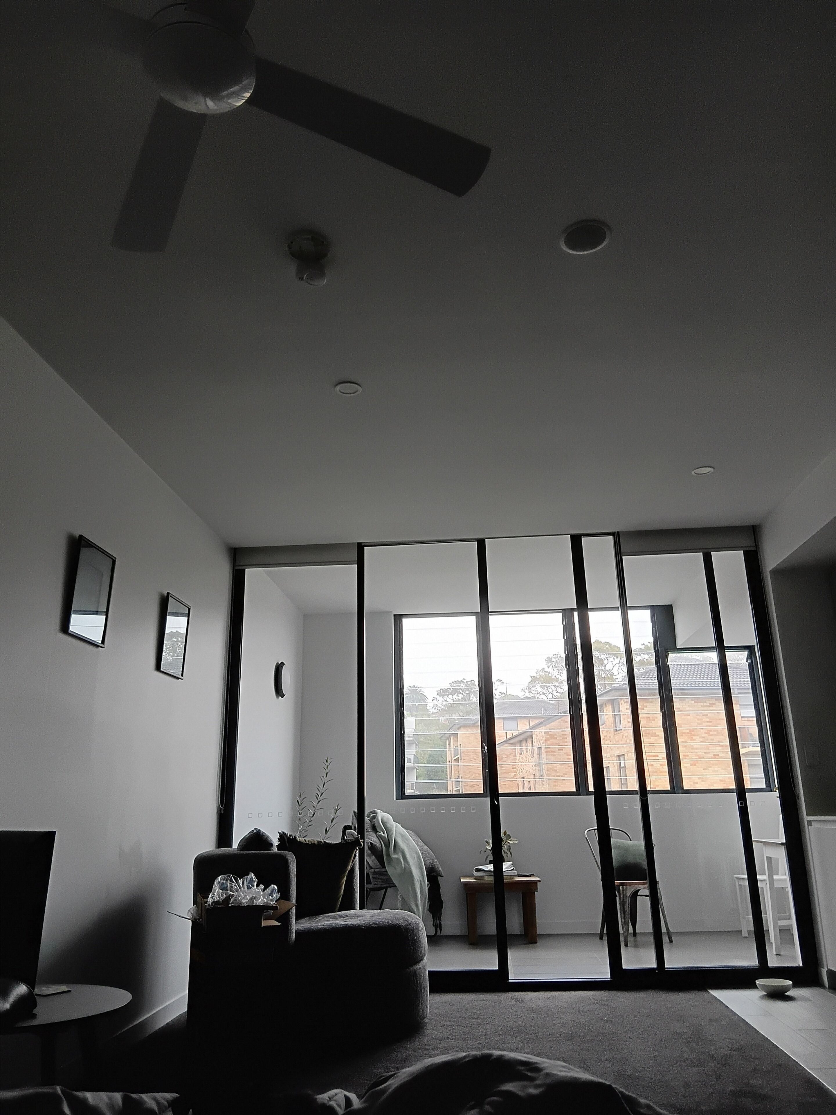 A modern room with a large sliding glass door, a ceiling fan, and a view of a building outside.