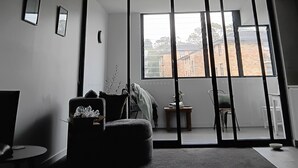 Ein modernes Zimmer mit einer großen Schiebeglasdoor, einem Deckenventilator und Blick auf ein Gebäude.