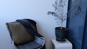 Eine Sitzecke mit einem Sessel, einem kleinen weißen Hocker und einem Blumentopf.