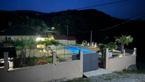 En boligejendom med swimmingpool, lukket have og en skråning i baggrunden.