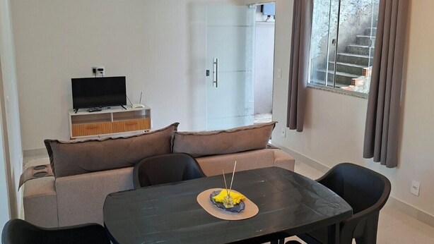 A modern living room with a sofa, a dining table with chairs, a TV, and a unique ceiling light fixture.