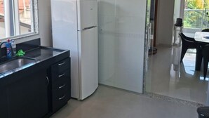A modern kitchen with a refrigerator, a sink, and a dining area with a table and chairs.