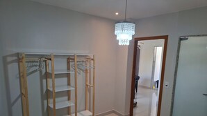 A bedroom with a bed, a wooden wardrobe, a chandelier, and a door.