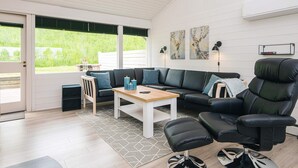 A modern living room with a sectional sofa, a black leather chair, a small table, and a rug. - 4 Star Holiday Home in Aabenraa (Aabenraa)