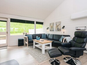 A modern living room with a sectional sofa, a black leather chair, a small table, and a rug. - 4 Star Holiday Home in Aabenraa (Aabenraa)