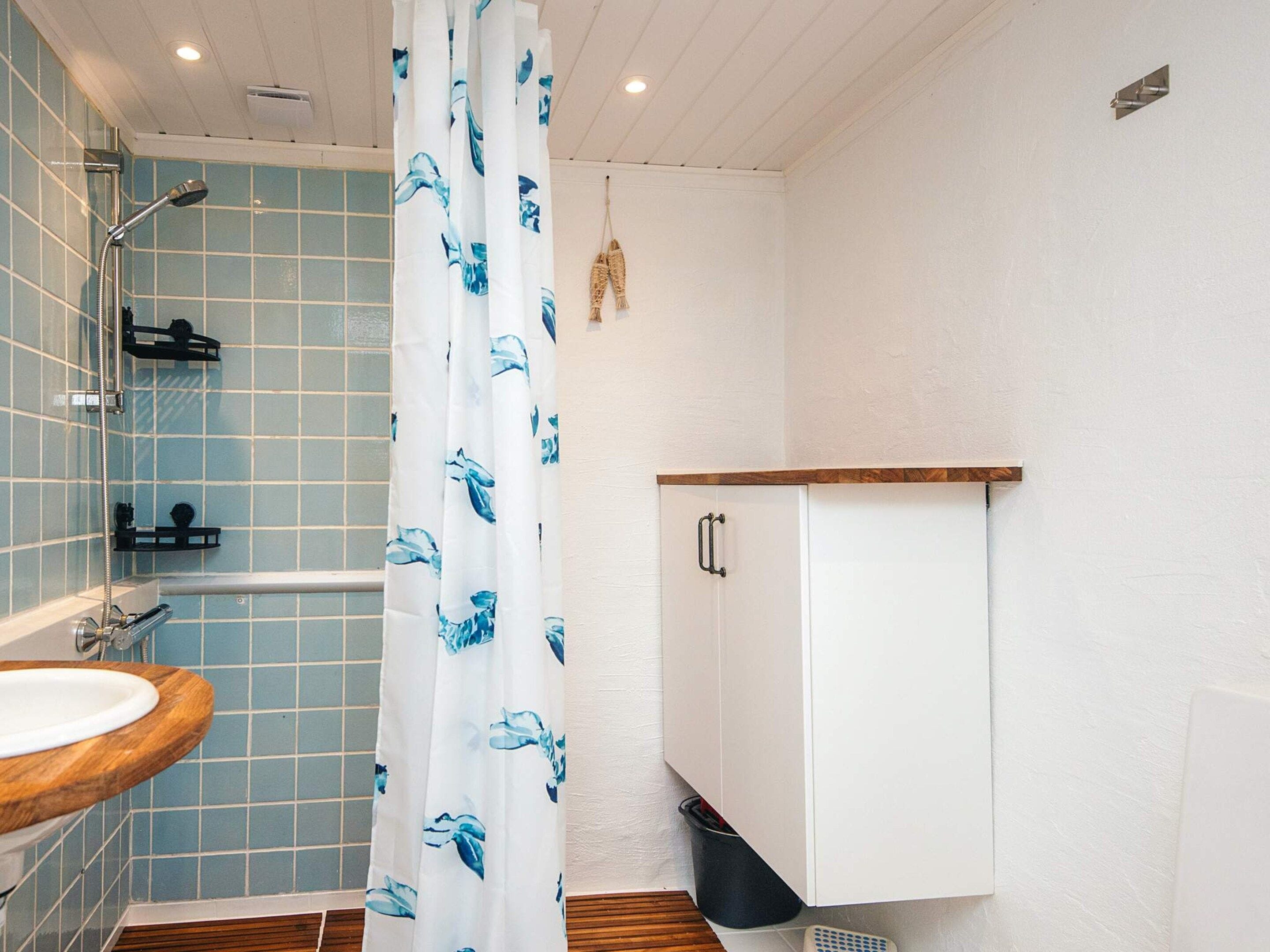 Ein Badezimmer mit Dusche, einem Waschbecken mit Holzbeschlag und einem Schrank.