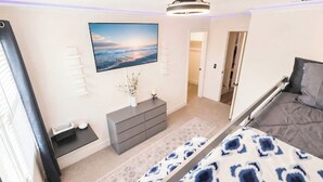 Ein Schlafzimmer mit Bett, Fernseher, Kommode und Fenster.
