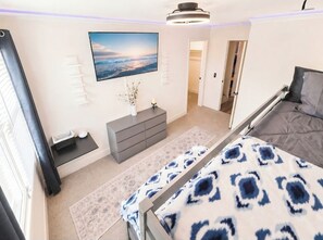 Ein Schlafzimmer mit Bett, Fernseher, Kommode und Fenster.
