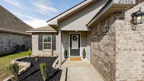 A residential house with a brick facade, a front door with a wreath, and a mailbox.